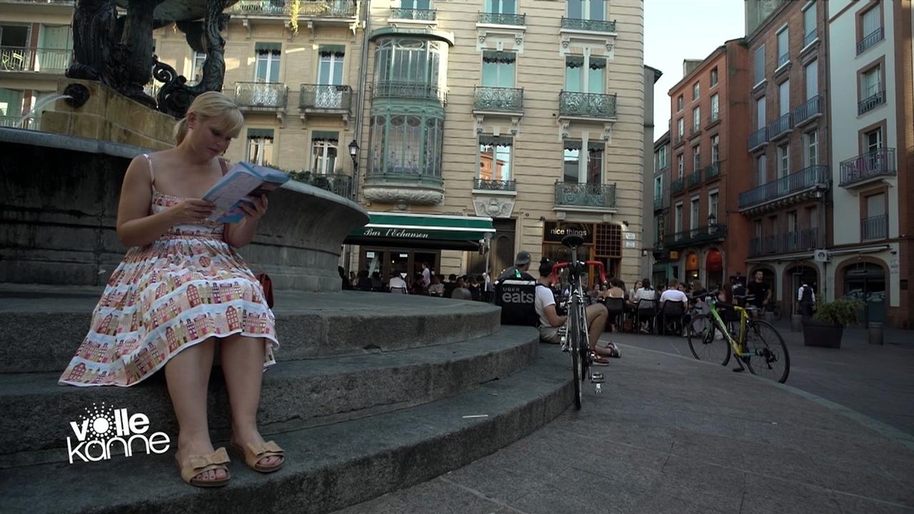 Femme assise lisant un livre devant le Restaurant Emile à Toulouse.